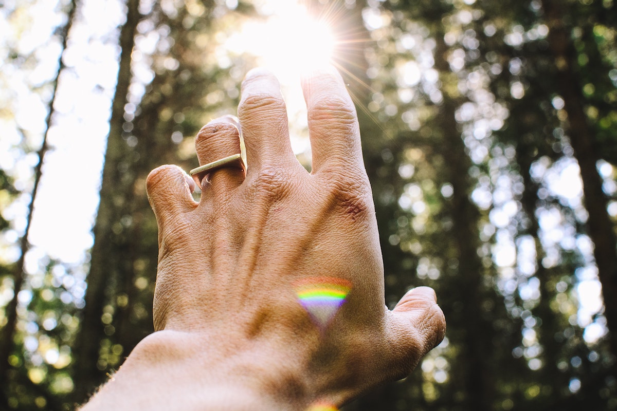 hand reaching to light with ring and triangle rainbow