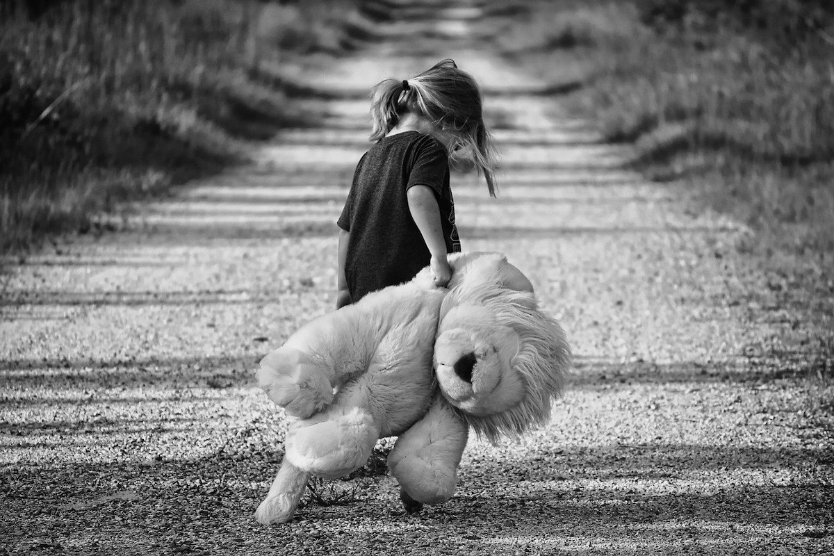 small girl carrying large teddy black and white